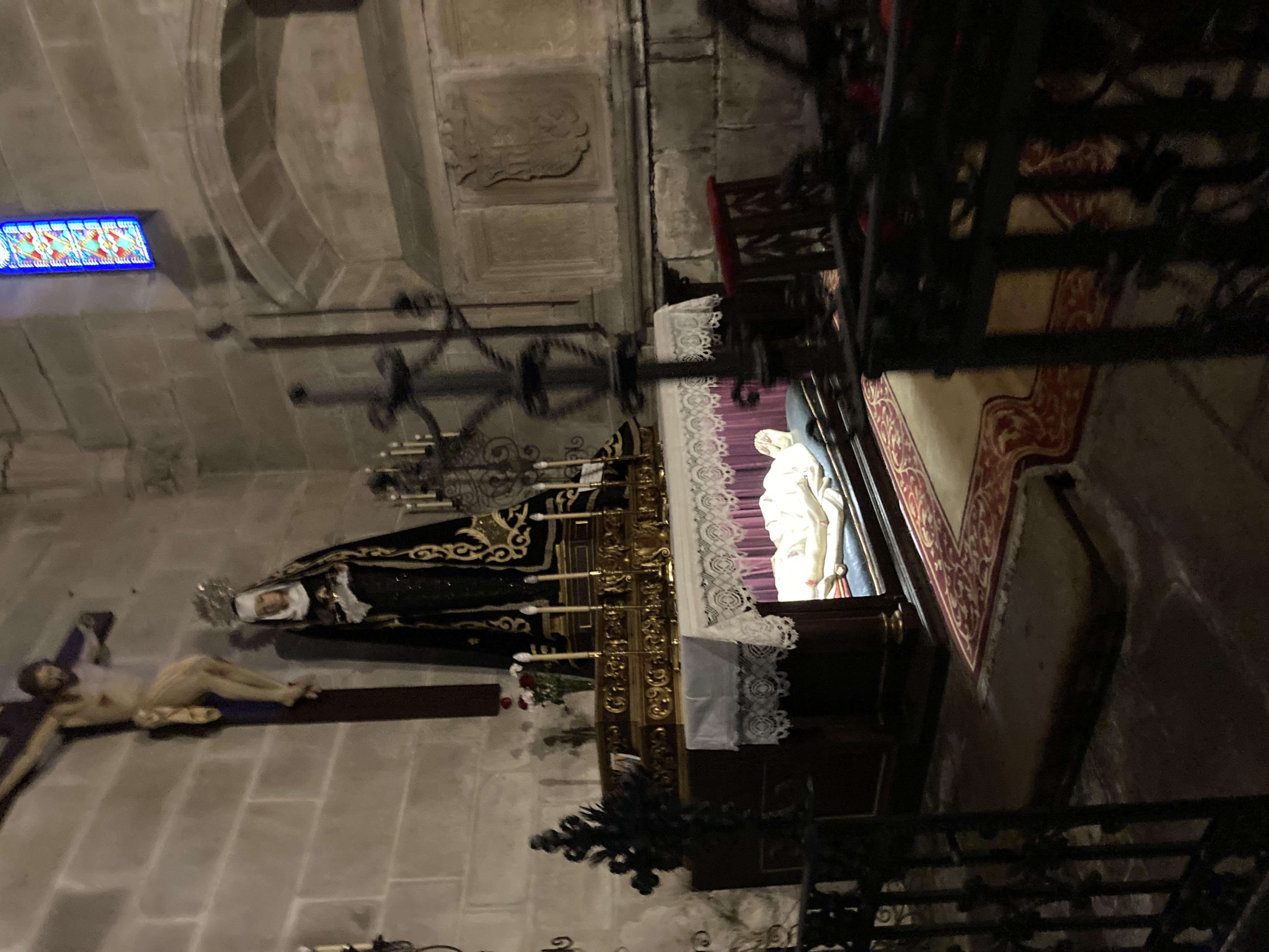 inside of church, holy figures on a side altar. Figure of a dead person in a box with light. Maybe some saint?