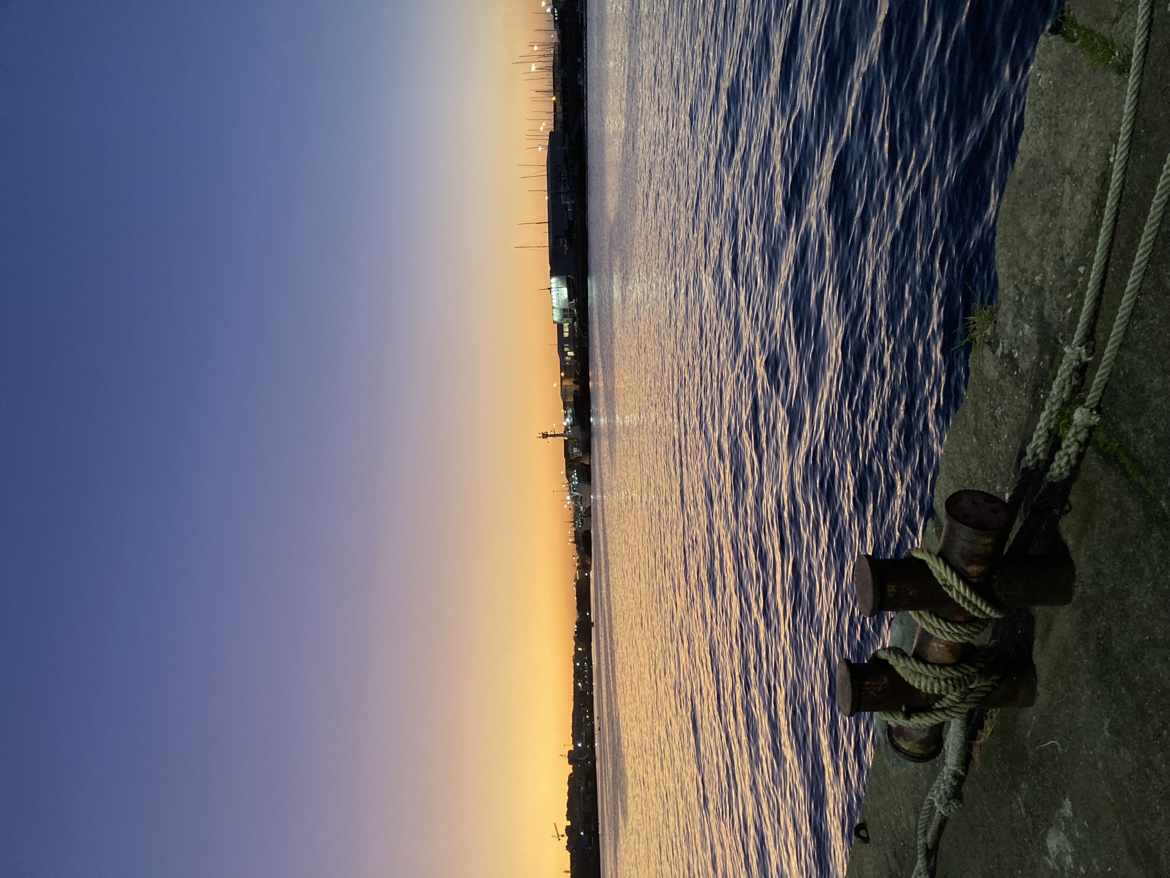 a fisherman sitting by the peer side in the early dusk